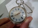 une personne tenant une montre de poche en argent ornée de chiffres romains