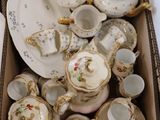 a cardboard box filled with a variety of antique teapots and saucers