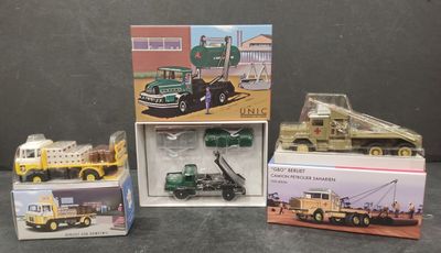 Plusieurs camions miniatures sont rangés dans des boîtes posées sur une table