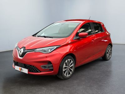 Une voiture rouge est garée dans une pièce au sol noir.