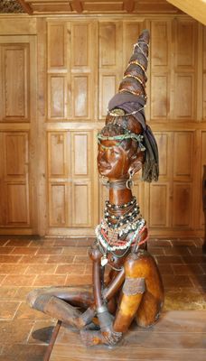 une statue représentant une femme assise sur un plancher en bois