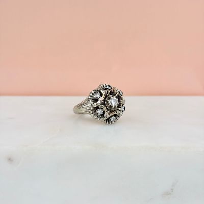un gros plan d'une bague posée sur une surface en marbre, sur fond rose
