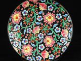 un gros plan d'une assiette noire ornée de fleurs colorées
