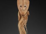 an image of a wooden mask with long hair on a stand