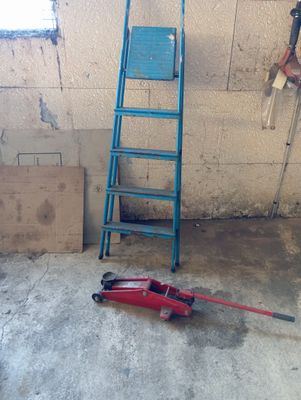 une échelle appuyée contre un mur, à côté d'une chaise bleue