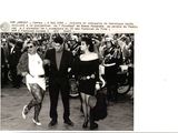 black and white photograph of a man and woman walking in front of a crowd of people