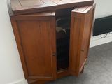 a wooden cabinet with a door open in the corner of a room