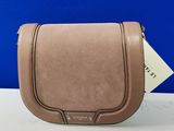 un sac à main en cuir beige posé sur une table blanche, sur fond bleu