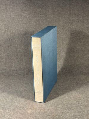 the blue book is sitting on a brown cloth covered surface