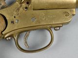 a brass gun with a wooden handle on a white surface