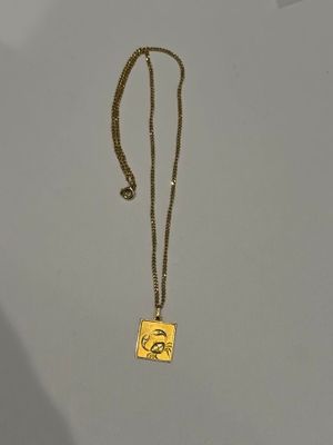 collier plaqué or avec un pendentif carré orné d'un visage