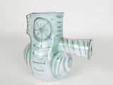 a green vase with a clock on it on a white surface