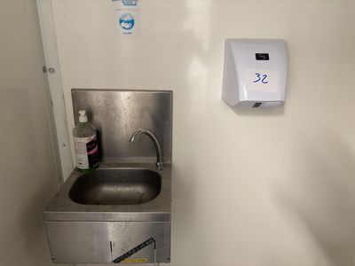 un évier en acier inoxydable et un sèche-mains dans une petite pièce
