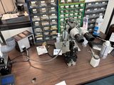 une photo représentant un microscope et d'autres appareils posés sur une table