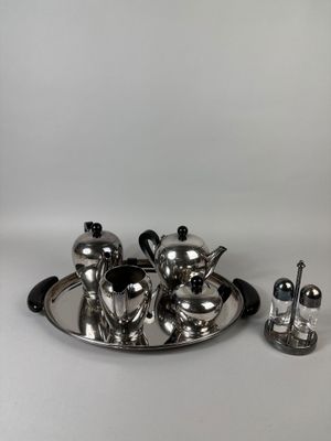 a silver plate with a silver teapot and a silver salt shaker on it