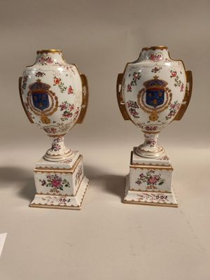 Deux vases sont posés sur une table devant un fond blanc.