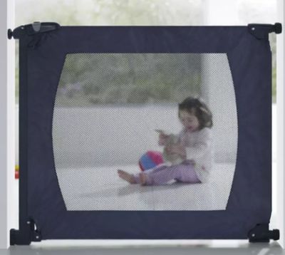 une petite fille assise devant une barrière de sécurité pour bébé