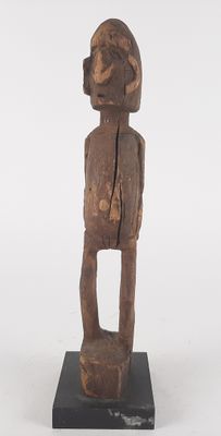 an old wooden statue of a man standing on a black base