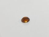 an oval shaped faceted citrine stone on a white surface