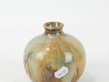 a small vase with a tag on it on a white surface