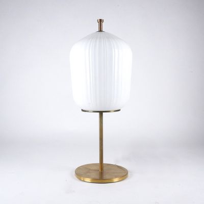 a white glass and brass table lamp on a gold base