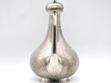 an old silver vase with a metal lid on a white surface