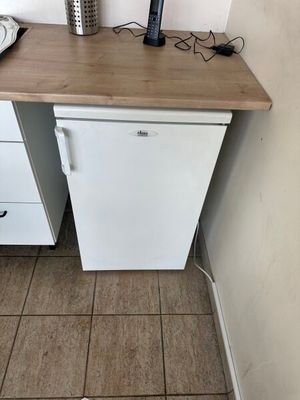 a small white refrigerator in a small kitchen