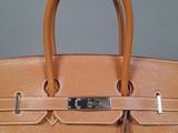 an image of a brown leather handbag with a padlock on it