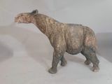 une statue représentant un rhinocéros debout à côté d'un vase de fleurs