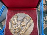 a gold medal in a red box on a blue chair
