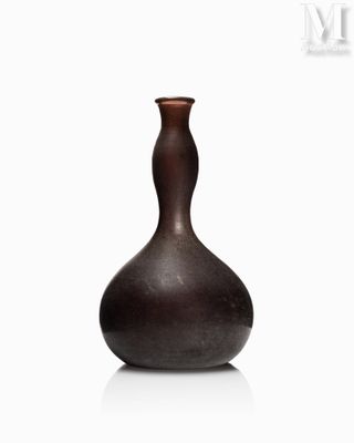 un vase brun posé sur une surface blanche