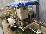 une bâche bleue à l'arrière d'une remorque, à laquelle est fixée une pompe à eau
