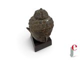 statue of a buddha head on a wooden base with a white background
