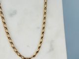 un gros plan d'un collier à chaîne en or posé sur une surface en marbre