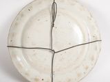 a white plate with wire wrapped around it on a white surface