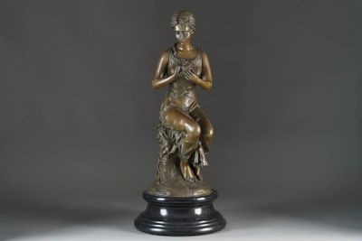 bronze statue of a woman holding a bird on a pedestal