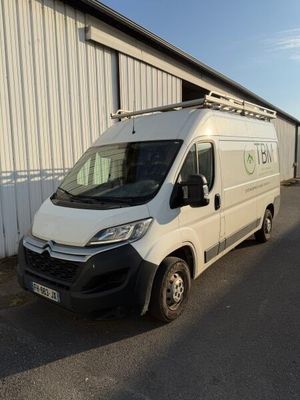 La camionnette est garée devant un immeuble sur lequel est accrochée une pancarte.