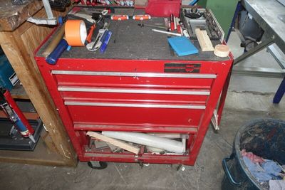 une boîte à outils rouge posée dans un garage, avec des outils dessus