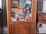 a wooden cabinet with a glass door in the corner of a room