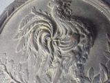 a silver coin with a rooster on it on a table