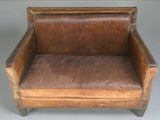 fauteuil en cuir marron avec des accoudoirs et des pieds cloutés