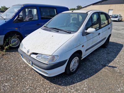 a small white car parked in a lot next to a blue van