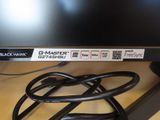 a black computer monitor sitting on a desk next to a charger