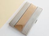 a silver and gold business card case sitting on a white table
