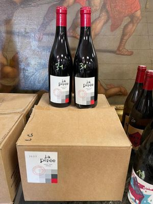 three bottles of wine sit on top of boxes in front of a painting