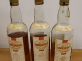 three bottles of whisky sitting on top of a wooden table