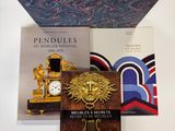plusieurs livres posés sur une table sur laquelle se trouvent une horloge et un livre