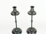 pair of metal candlesticks on a white surface with a white background