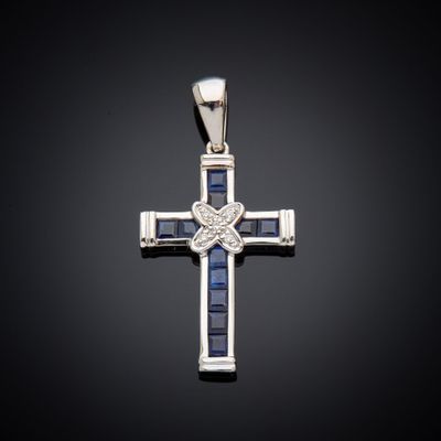une croix en or blanc sertie de saphirs bleus et de diamants sur fond noir
