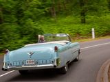 a blue car driving down the road with a man in the back seat